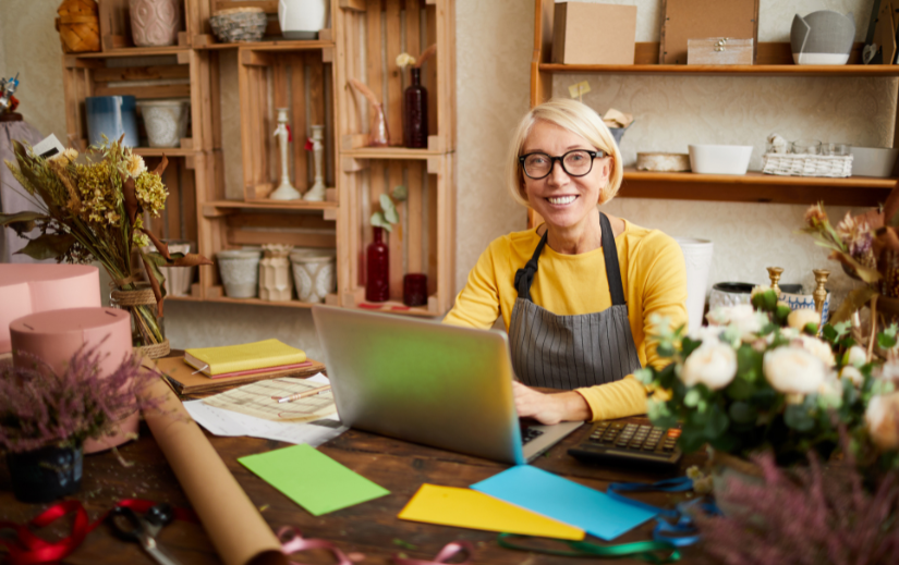 Smiling florist using a laptop in her shop, learning SEO for beginners to grow her small business online.